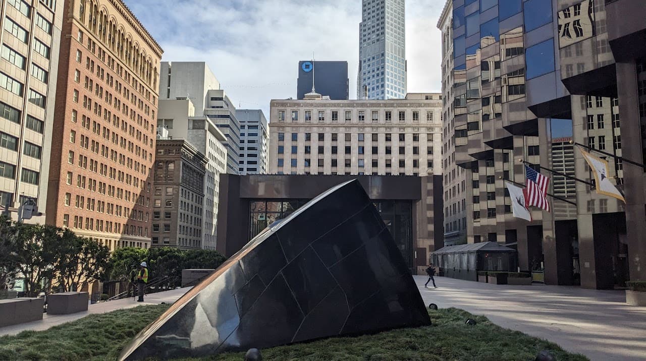 The Transcendence monument's dark surface reflects American high rises at midday